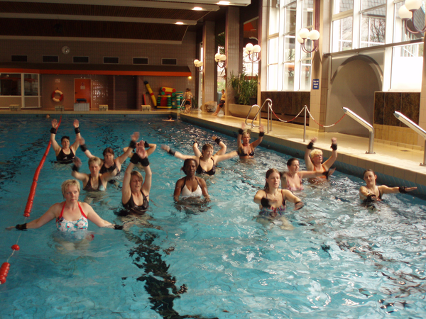 Eine Gruppe von Frauen macht in einem Hallenbad Wasserübungen.